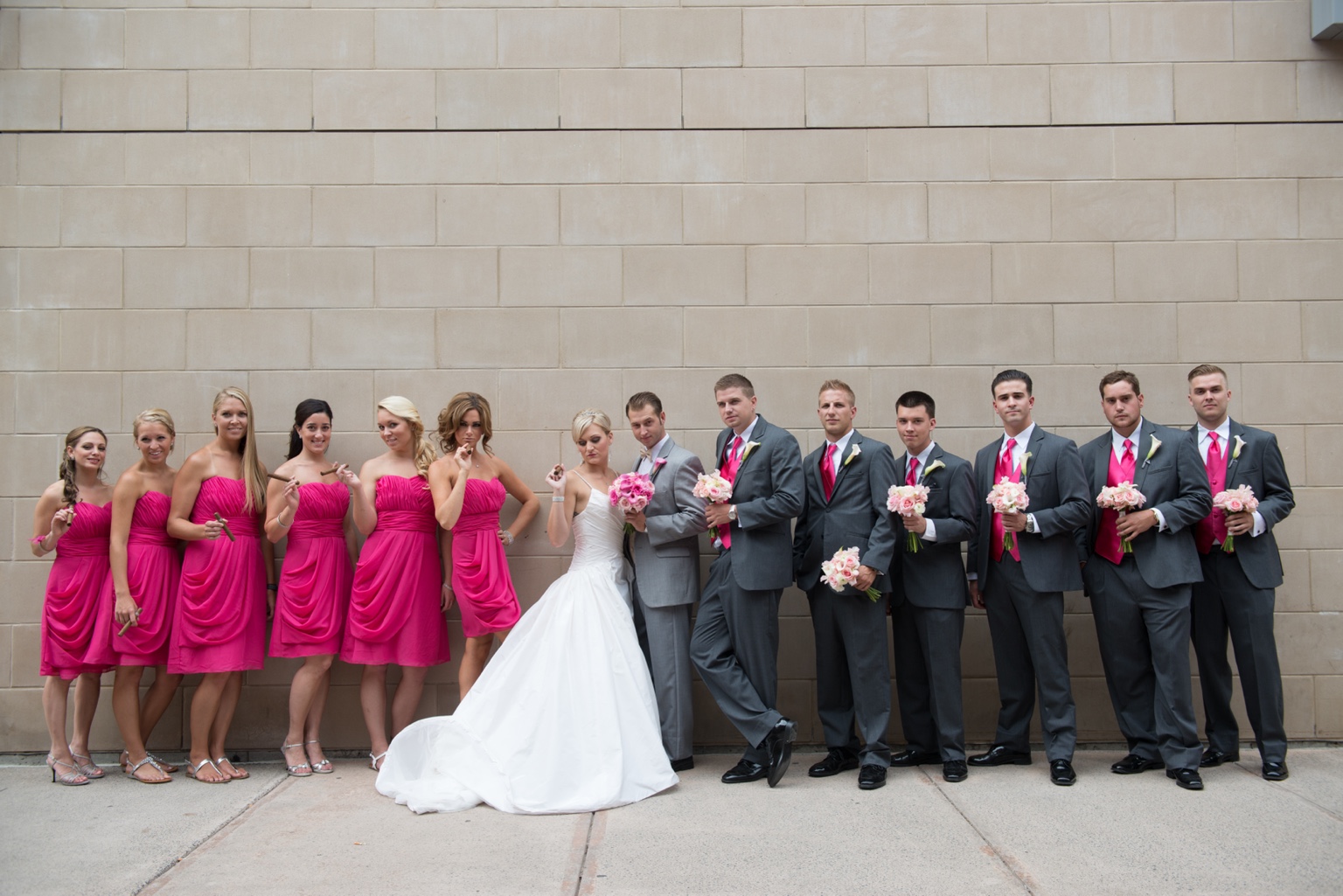 Bride and groom with their wedding party in pink dresses and charcoal suits